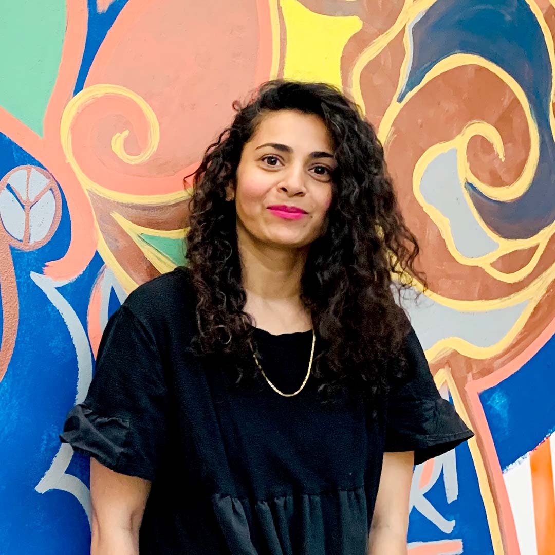 Photo of Zahra Ali artist against her mural in mid town Houston